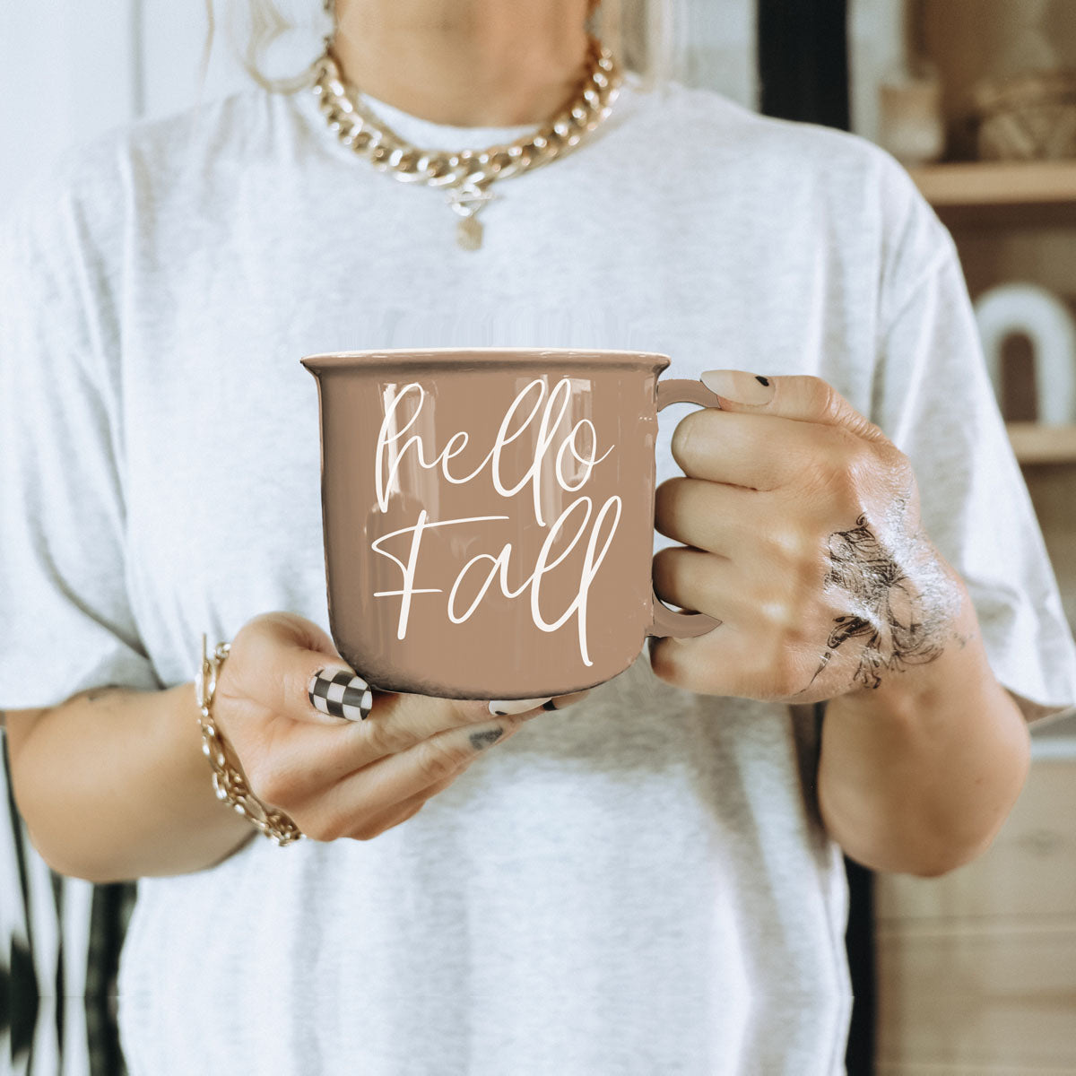 hello fall coffee cup on wicker tray
hello fall mug in fall bedroom nightstand decor
hello fall mug on porch with pumpkins and mums
hello fall mug in fall kitchen window light